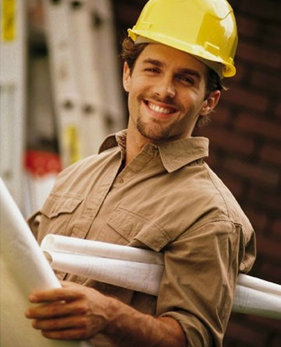 Smiling Contractor At Worksite Holding Blueprints